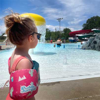 child with water wings looks at zero depth pool