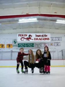brothers and sisters taking a picture in the ice arena